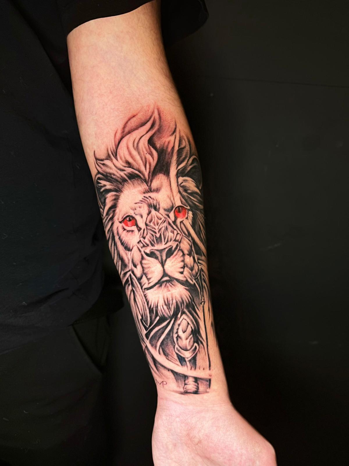 Lion and warrior forearm tattoo in black and grey by Déjà Vu Tattoo