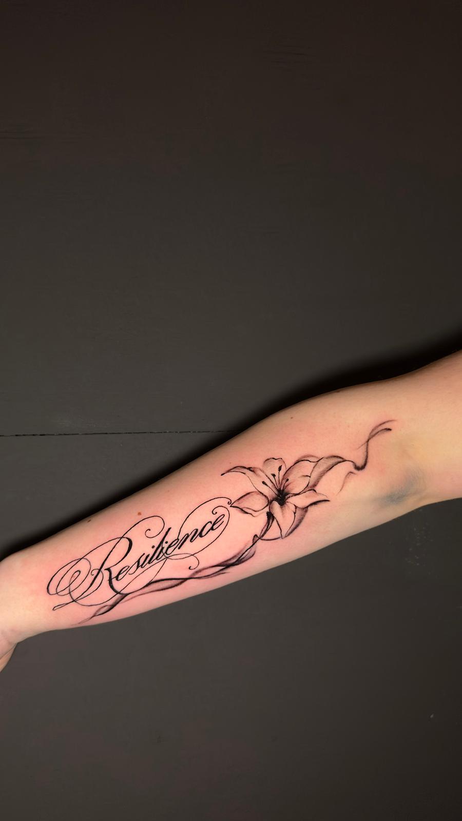 Script lettering with lily on the forearm